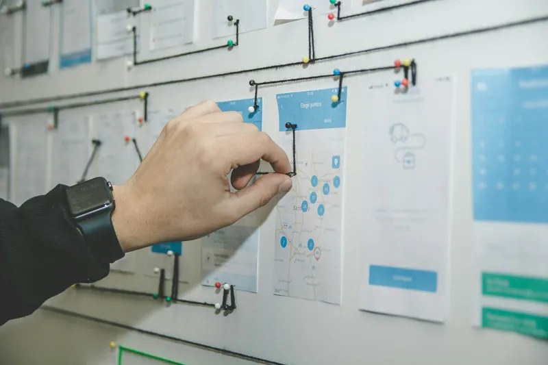 A designer pinning interface wireframes to a planning board
