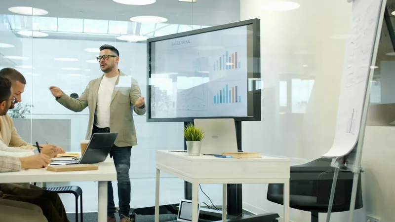 A presenter walking colleagues through charts on a large screen