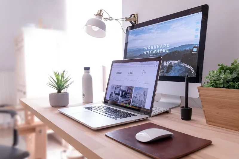 A website open on a laptop beside a desktop monitor